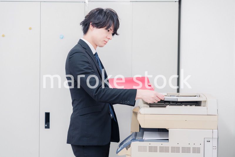 オフィスでコピーを取るスーツを着た男性
