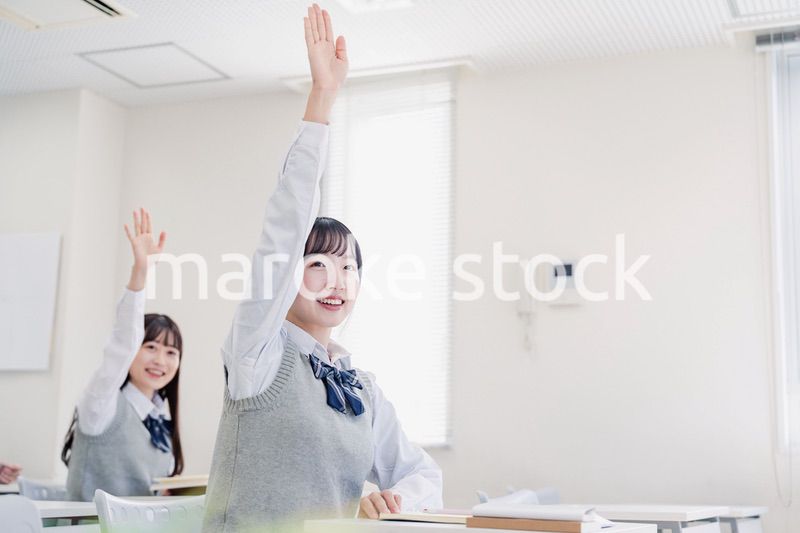 手を上げて発表をする女子高生