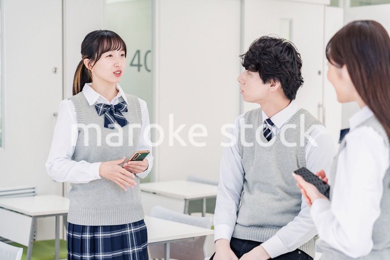 教室でクラスメイトと雑談をする高校生