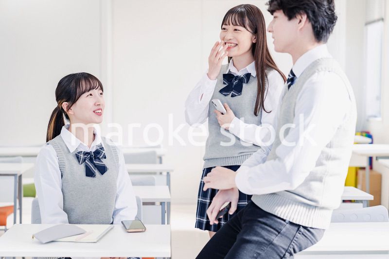教室でクラスメイトと雑談をする高校生