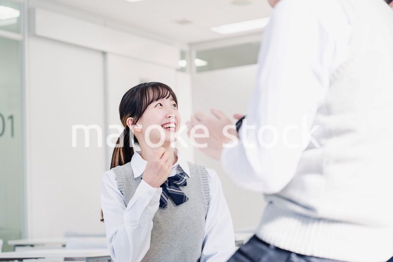 教室でクラスメイトと雑談をする高校生