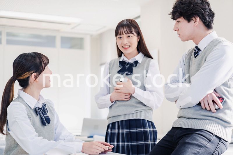 教室でクラスメイトと雑談をする高校生