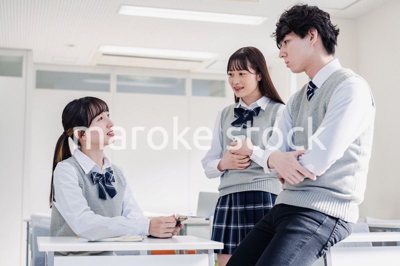 教室でクラスメイトと雑談をする高校生