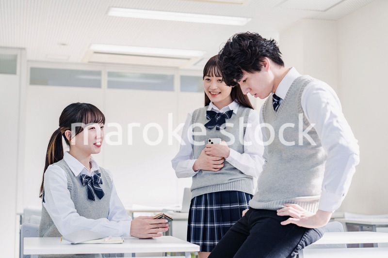 教室でクラスメイトと雑談をする高校生