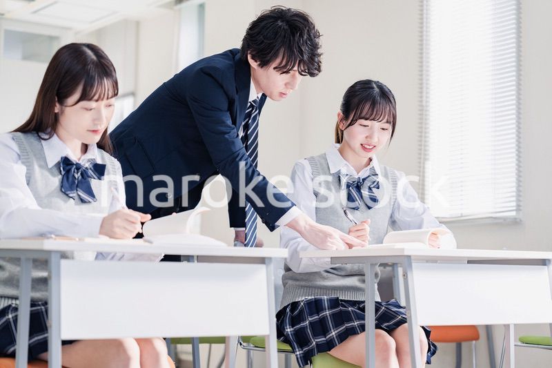 教室で先生に質問をする高校生
