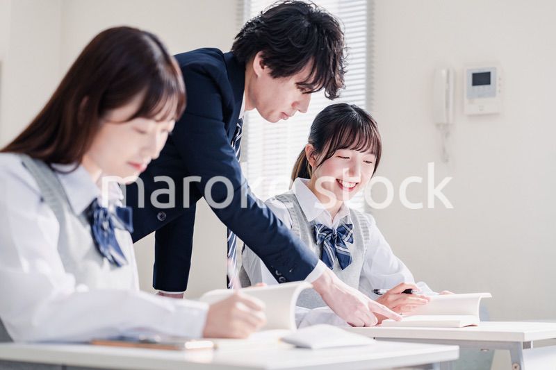 教室で先生に質問をする高校生