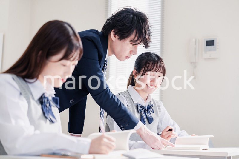 教室で先生に質問をする高校生