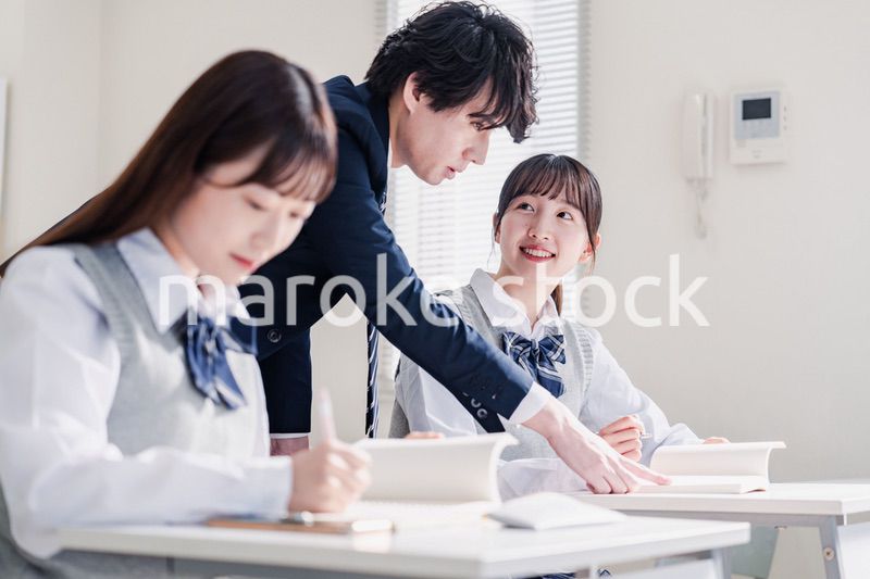教室で先生に質問をする高校生