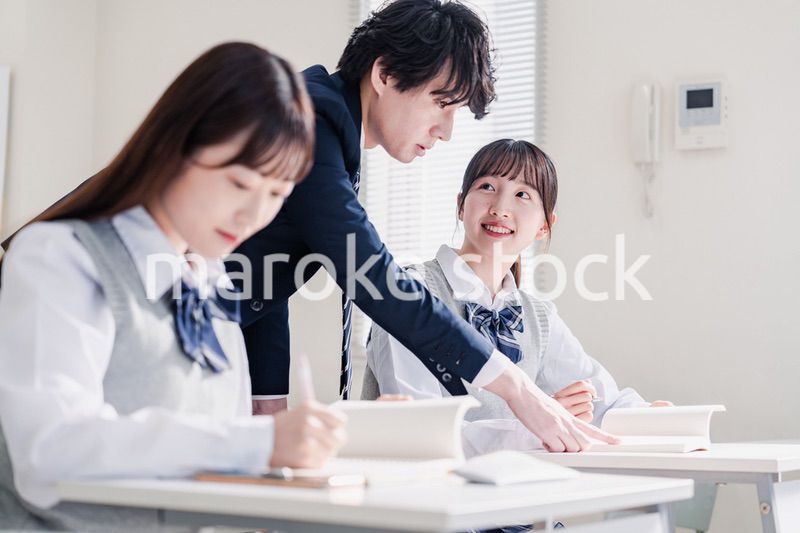 教室で先生に質問をする高校生