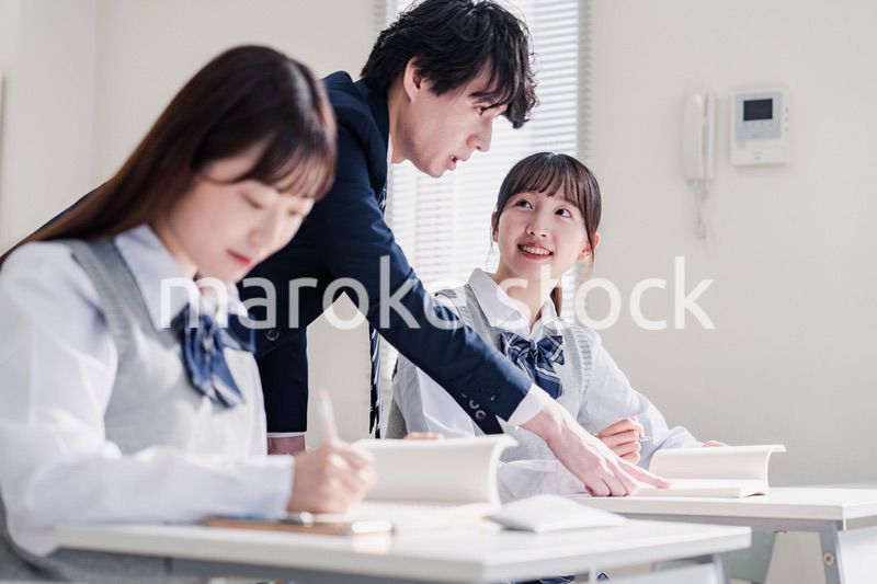教室で先生に質問をする高校生