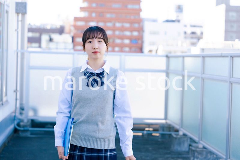学校の屋上を歩く女子高生