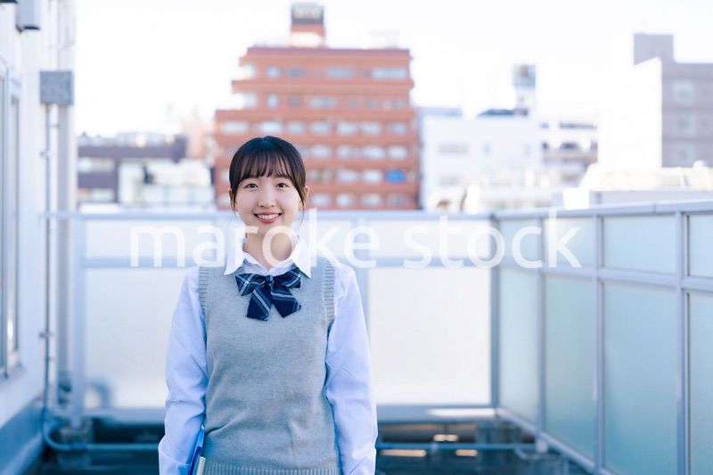 学校の屋上を歩く女子高生
