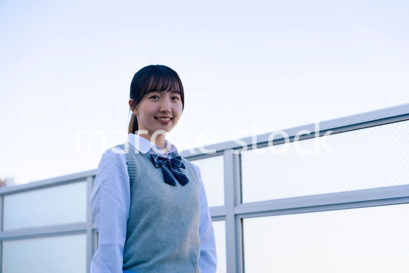 学校の屋上を歩く女子高生