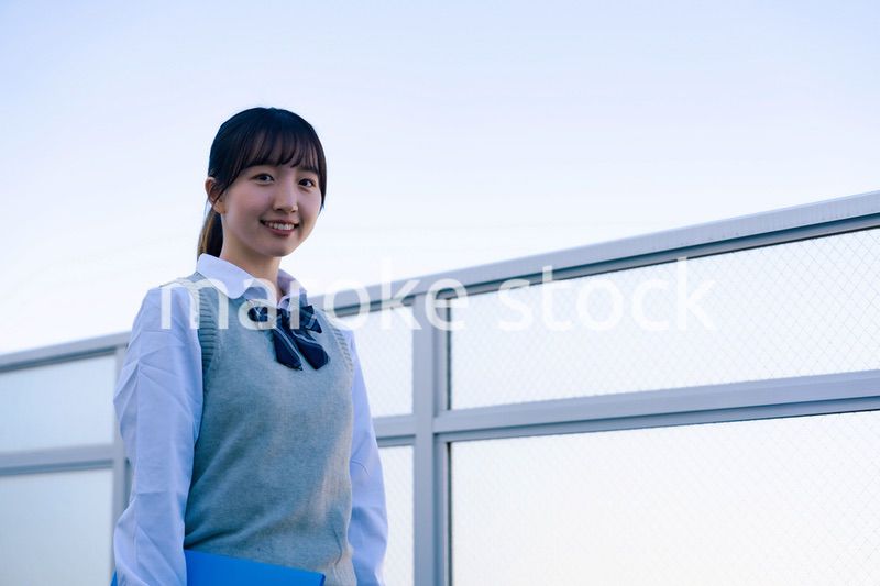 学校の屋上を歩く女子高生