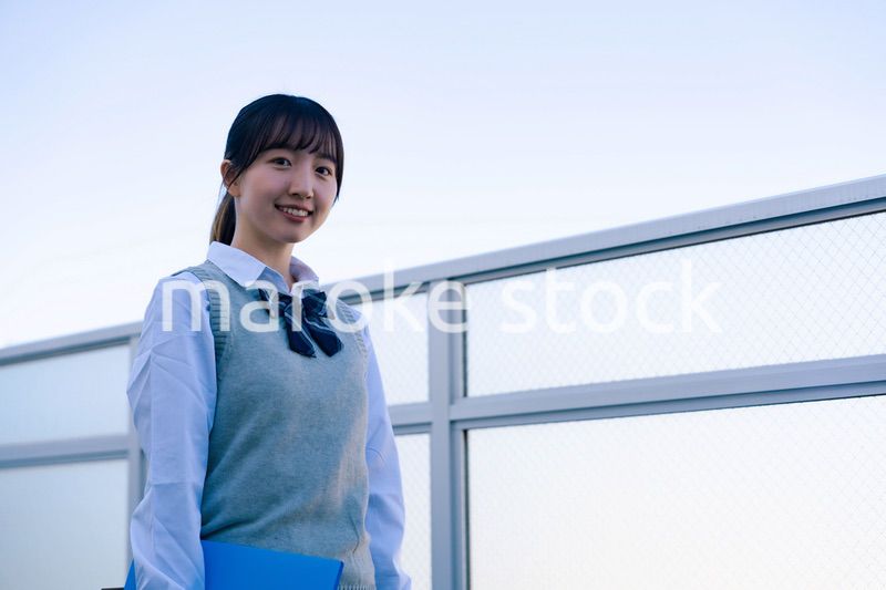 学校の屋上を歩く女子高生
