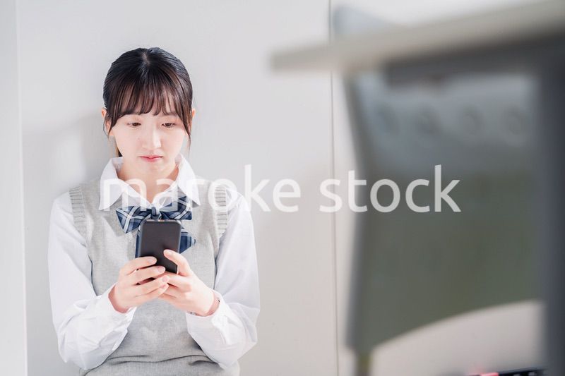 スマホを見ながら落ち込む女子高生