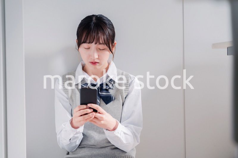 スマホを見ながら落ち込む女子高生