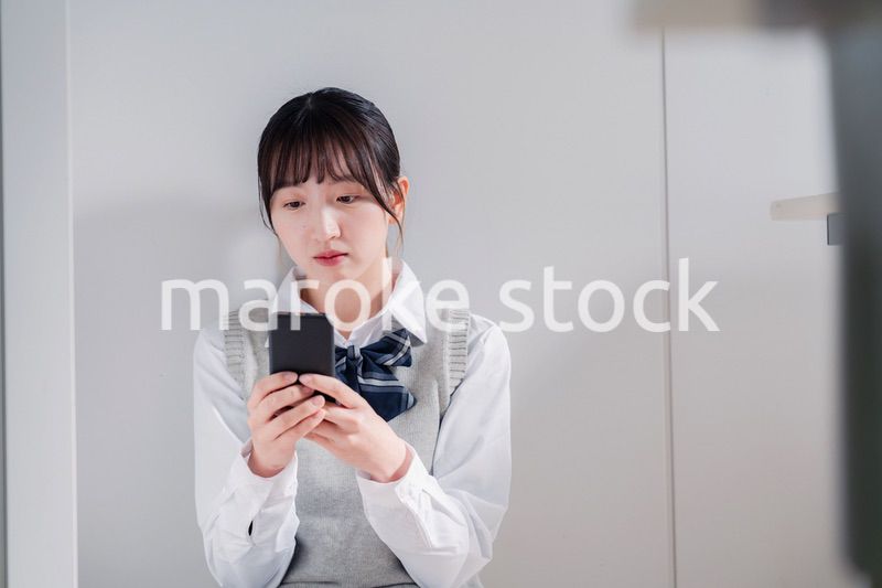 スマホを見ながら落ち込む女子高生