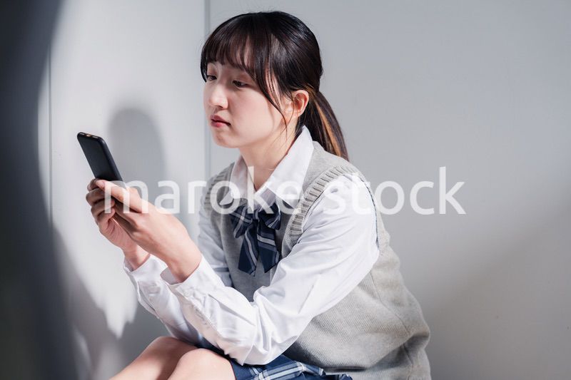 スマホを見ながら落ち込む女子高生