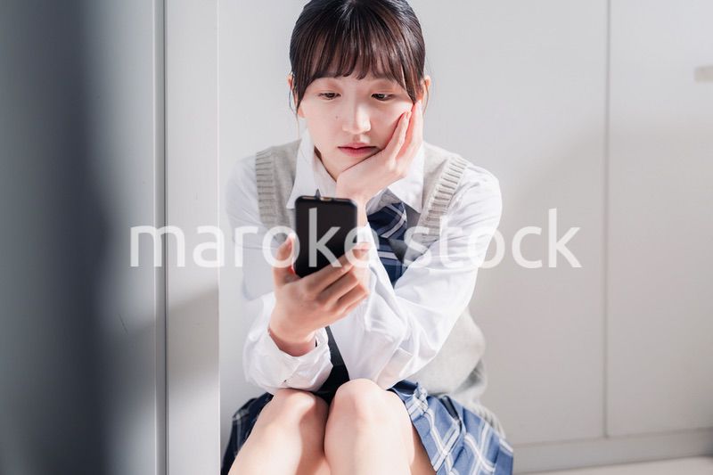 スマホを見ながら落ち込む女子高生