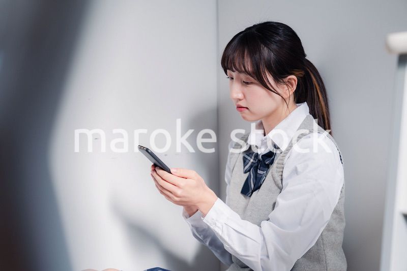 スマホを見ながら落ち込む女子高生
