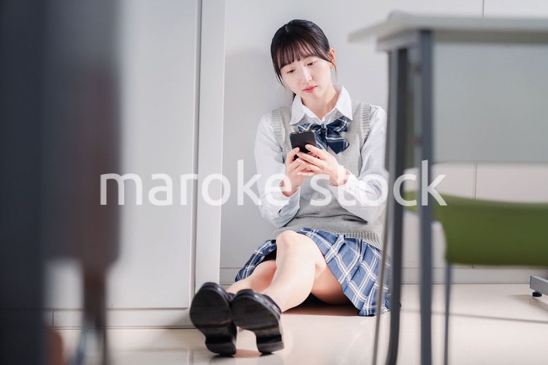 スマホを見ながら落ち込む女子高生