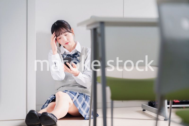 スマホを見ながら落ち込む女子高生