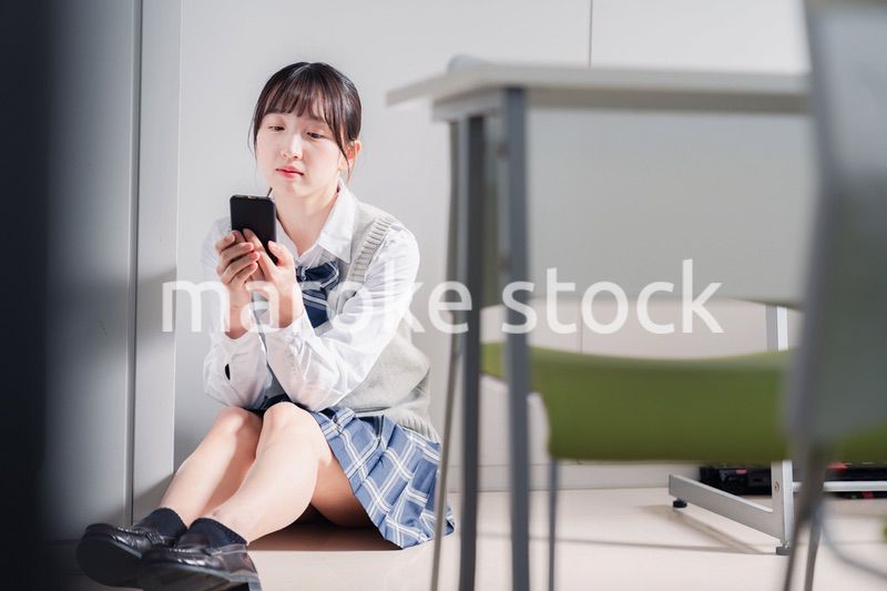 スマホを見ながら落ち込む女子高生