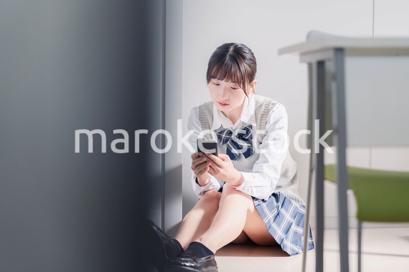 スマホを見ながら落ち込む女子高生