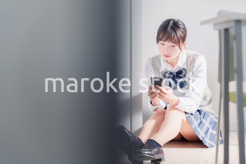 スマホを見ながら落ち込む女子高生