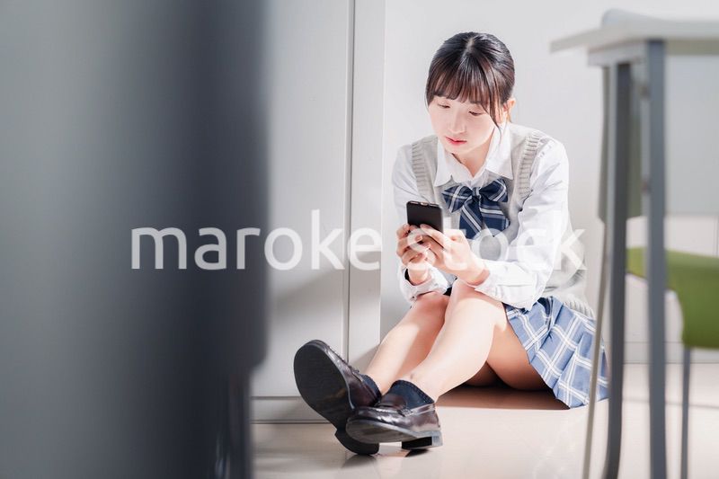 スマホを見ながら落ち込む女子高生