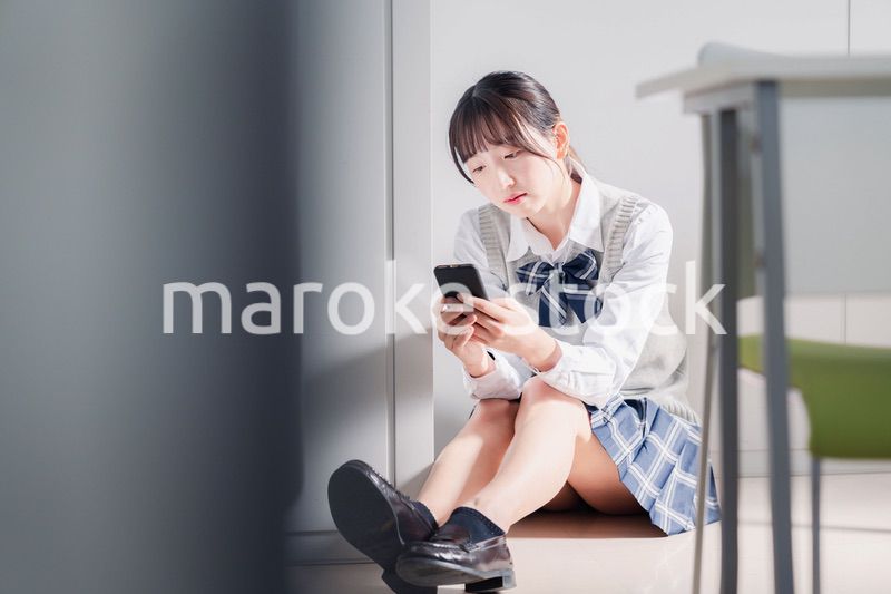 スマホを見ながら落ち込む女子高生