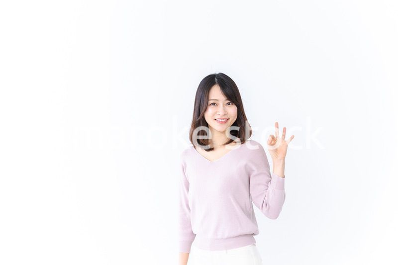 笑顔でグッドサインを示す若い女性