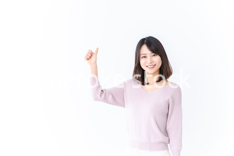 笑顔でグッドサインを示す若い女性