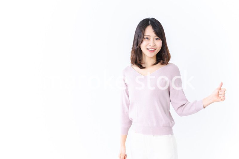 笑顔でグッドサインを示す若い女性