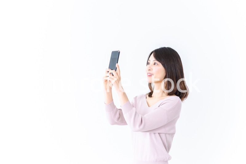 笑顔でスマホ撮影をする若い女性