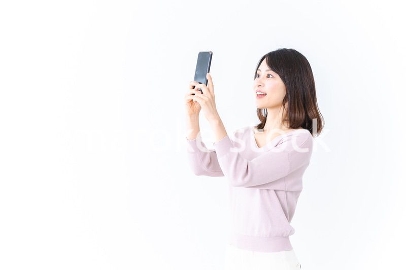 笑顔でスマホ撮影をする若い女性