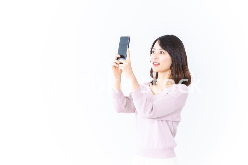 笑顔でスマホ撮影をする若い女性