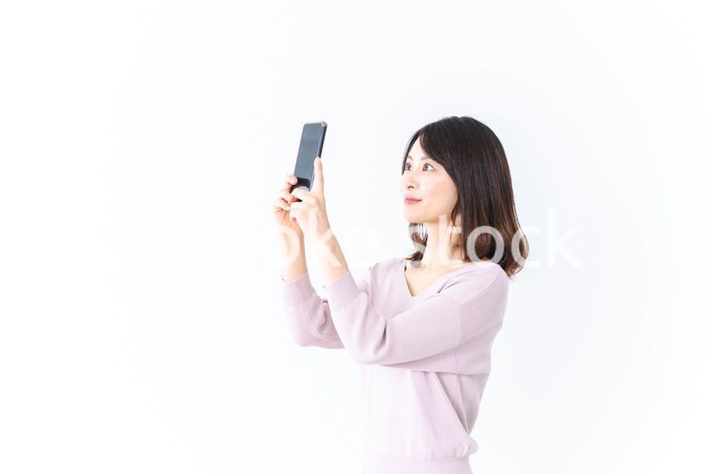 笑顔でスマホ撮影をする若い女性