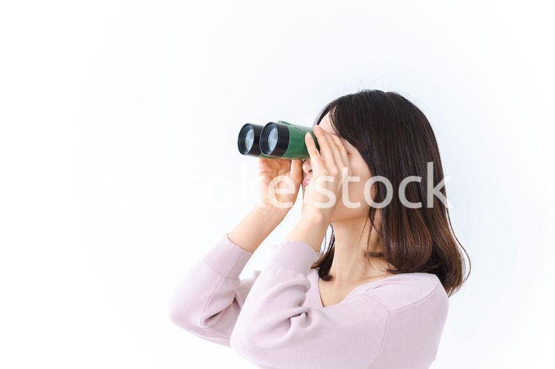 双眼鏡で遠くを見る若い女性