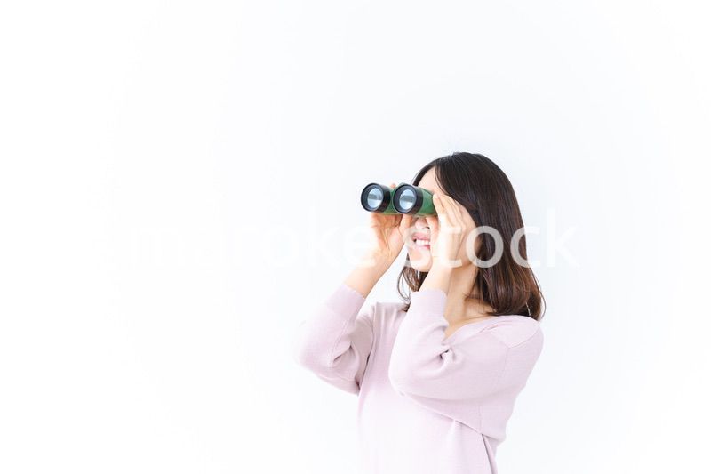 双眼鏡で遠くを見る若い女性