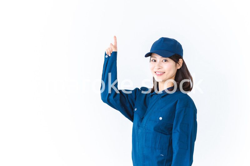 作業服を着て笑顔で指差す若い女性