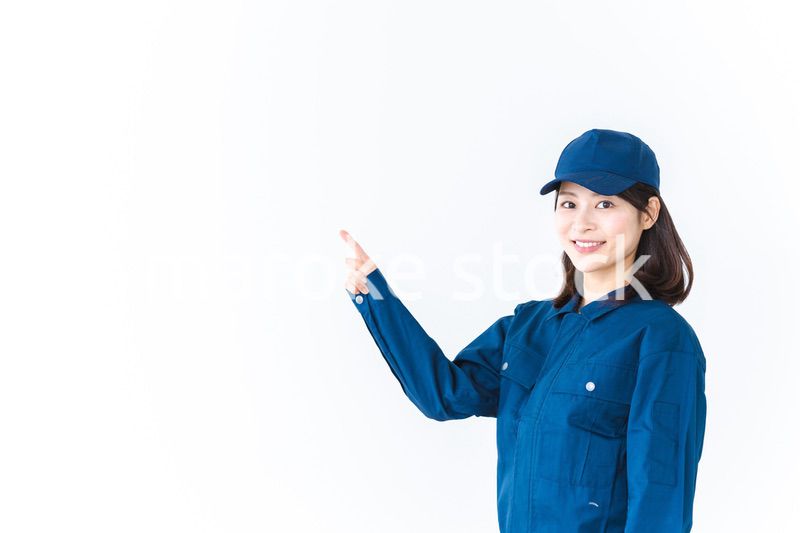 作業服を着て笑顔で指差す若い女性