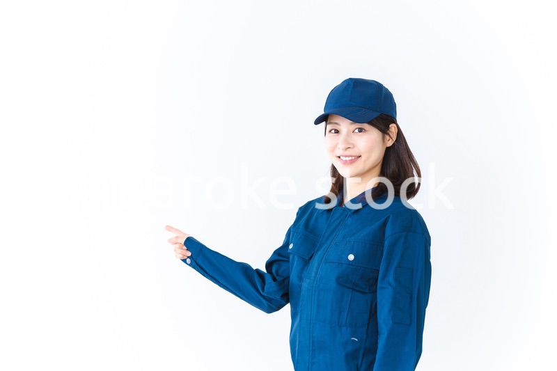 作業服を着て笑顔で指差す若い女性