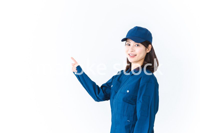 作業服を着て笑顔で指差す若い女性