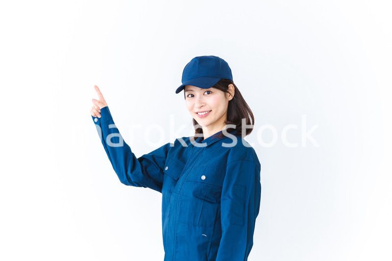 作業服を着て笑顔で指差す若い女性