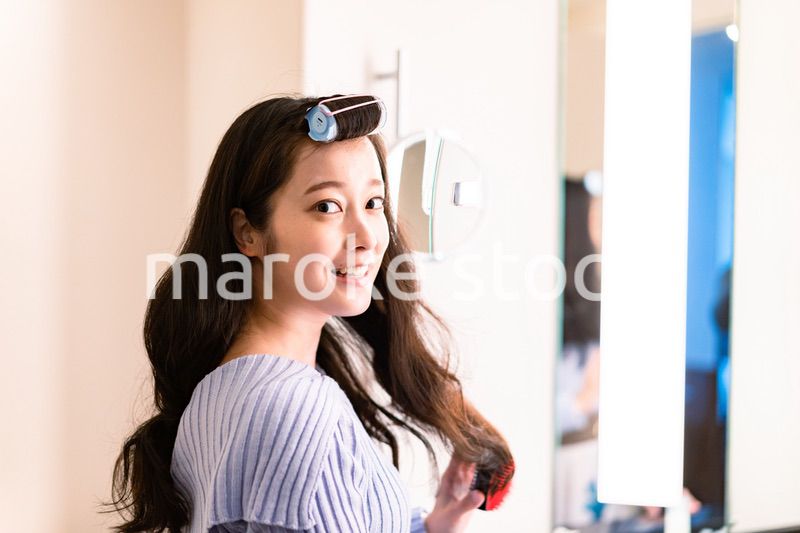 鏡の前で髪のセットをする若い女性