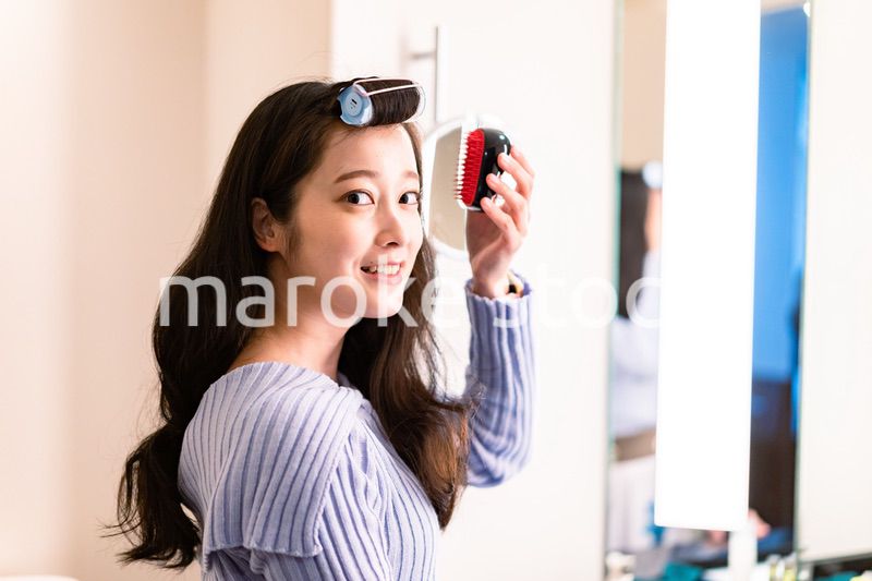 鏡の前で髪のセットをする若い女性