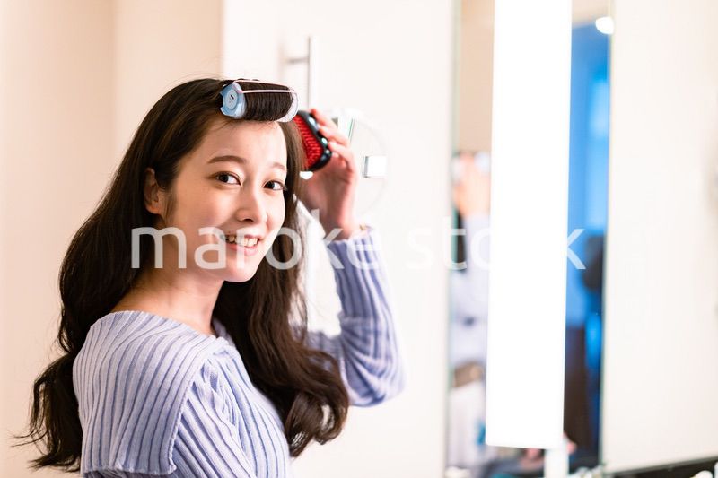 鏡の前で髪のセットをする若い女性