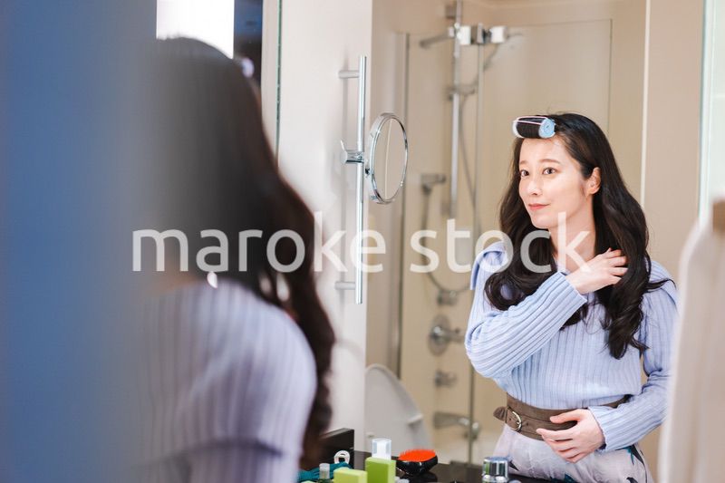 鏡の前で髪のセットをする若い女性